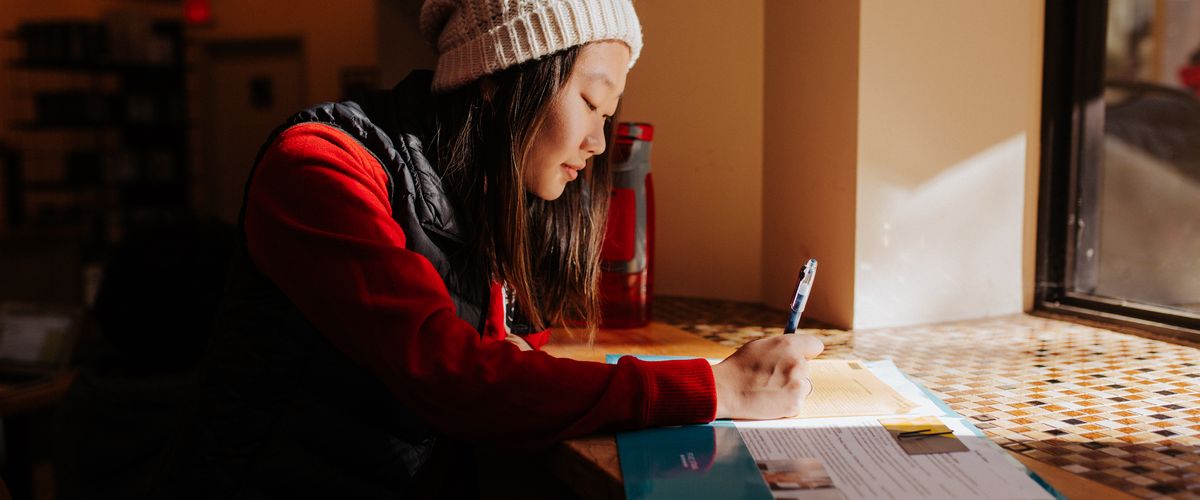 Student writing at a desk