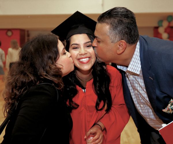 parents kissing daughter at BU graduation