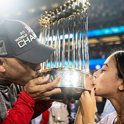 Red Sox manager Alex Cora and his daughter Camila kiss the World Series trophy.