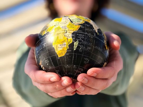 A person holding a small globe