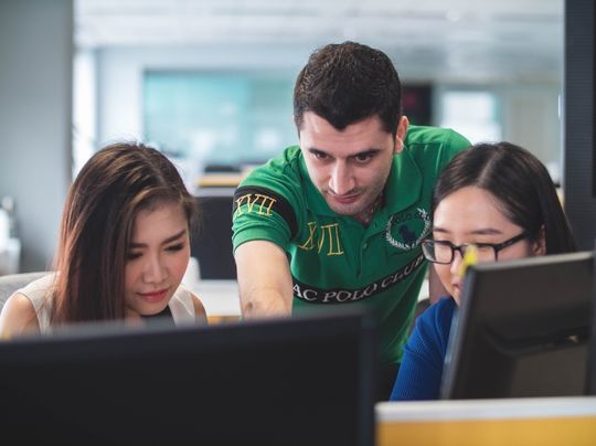 A man shows two woman something on a computer