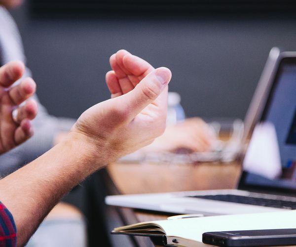 Hands gesticulating a woman is in the background