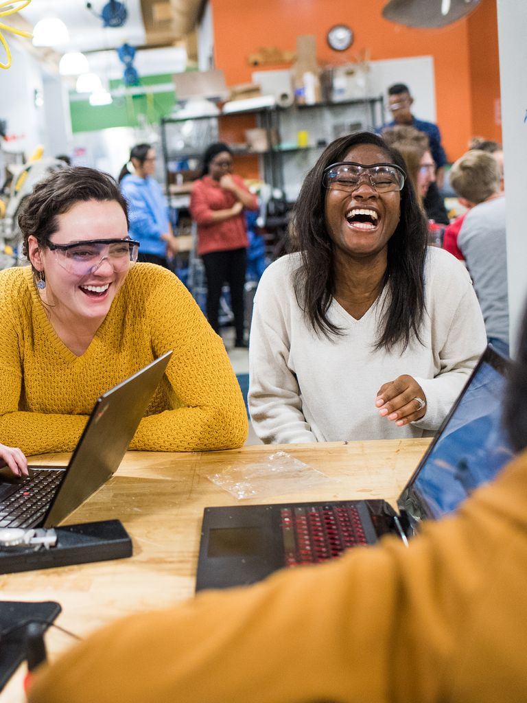 Female students smiling in a classroom wearing safety glasses