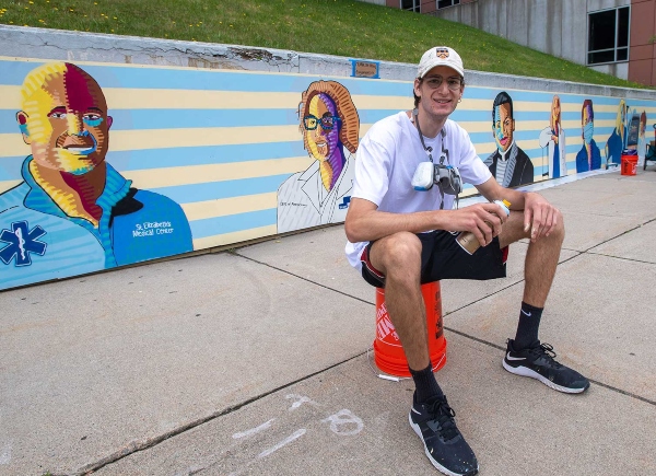 Sam Weinberger (CFA’21) in front of the mural he recently completed at St. Elizabeth’s Medical Center in Brighton.