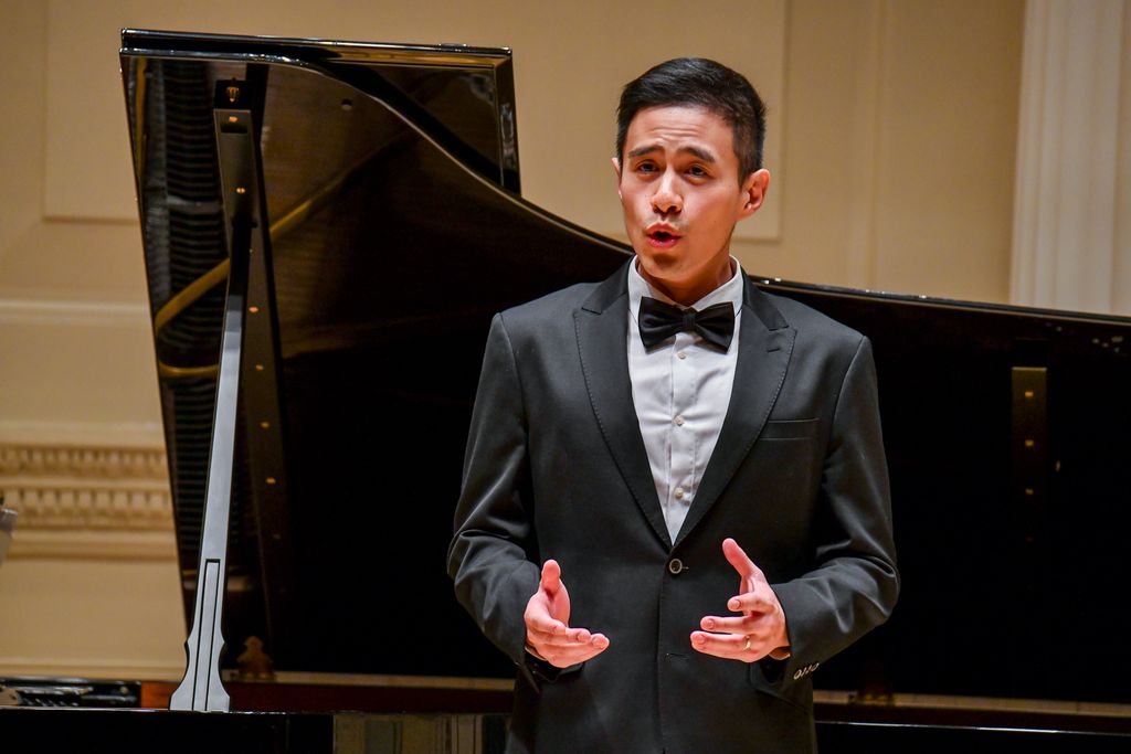 Singer in front of a piano performing for crowd on stage in Weill Recital Hall at Carnegie Hall for Boston University Spotlight Concert