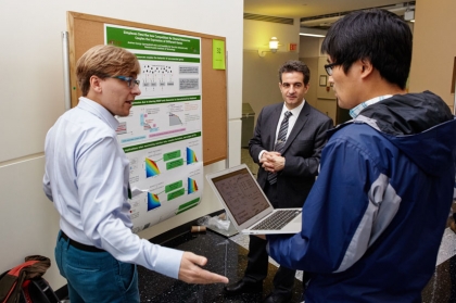 TCNS Editor-in-Chief Professor Yannis Paschalidis (ECE, SE, BME) (center) with MIT PhD student Andras Gyorgy (left) and another SCONES participant (right) during a poster session.