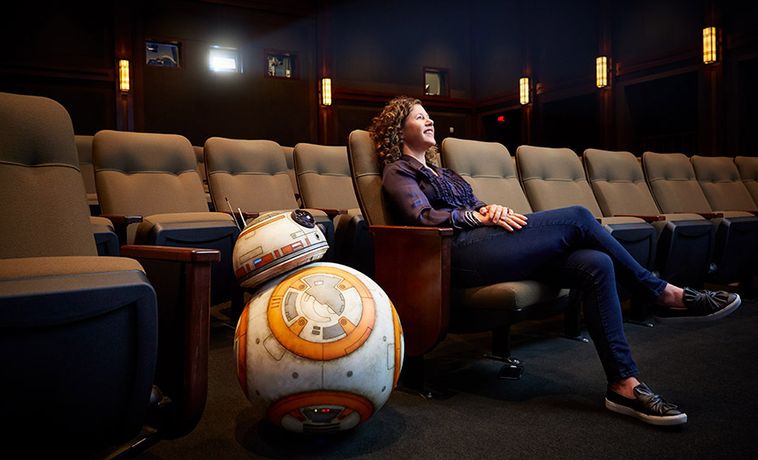 Janet Lewin sits in a theater with Star Wars droid BB-8.