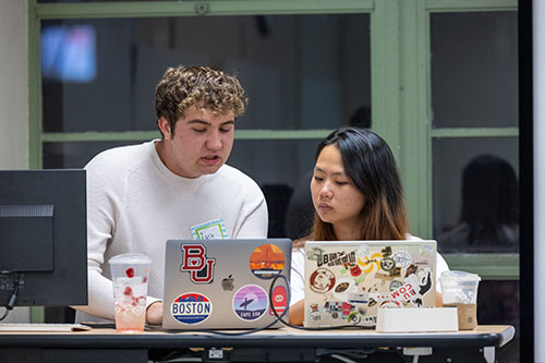 Young man and woman in conversation while standing behind a desk.
