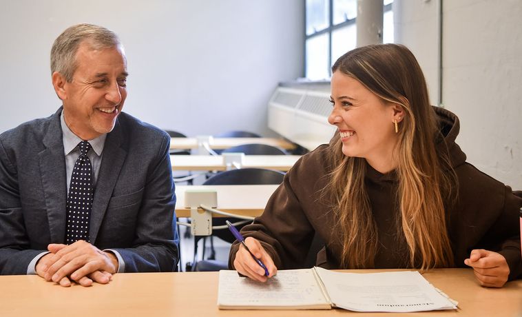 Michael Dowding sits at a table with a student.