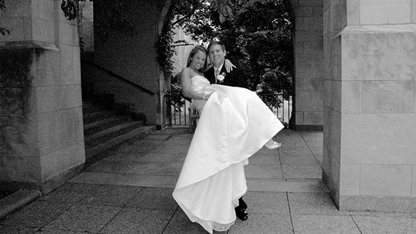 Ryan Kath carries his new bride Carla Kath in his arms at Marsh Chapel.