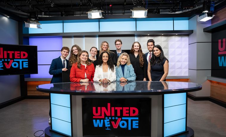 Students gathered around the anchor desk for United We Vote coverage.
