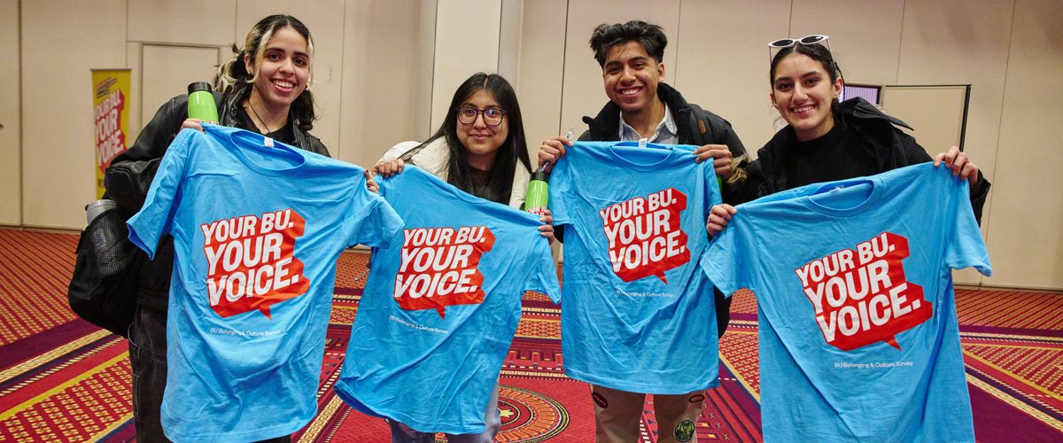 Students holding up blue t-shirts that read "Your BU. Your Voice"