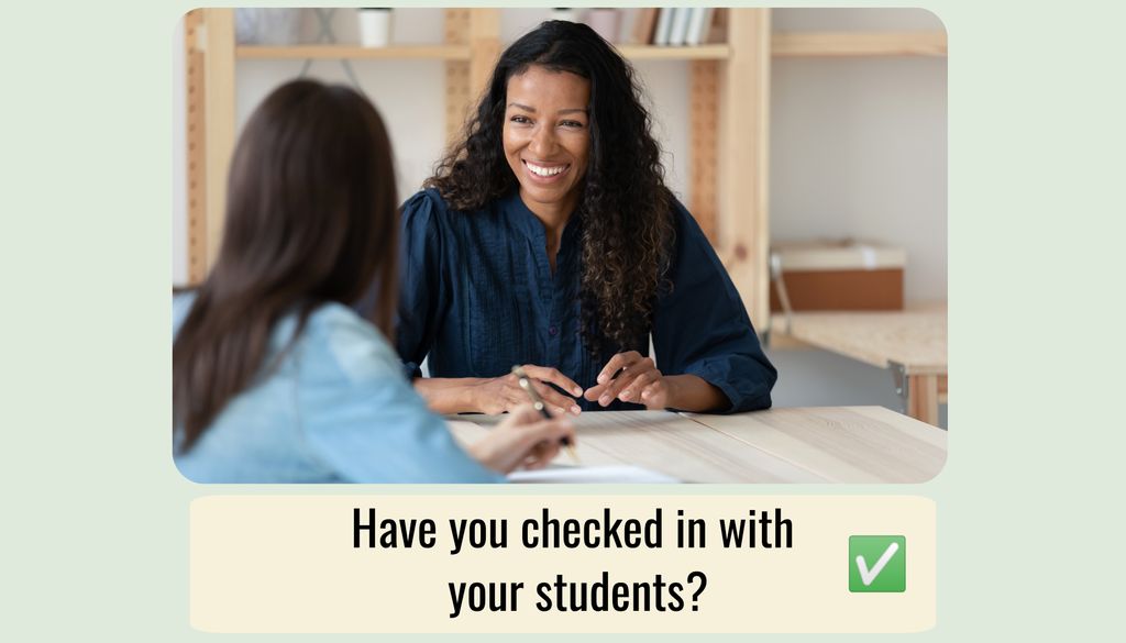 Image of black instructor smiling and working with a student at a desk. 