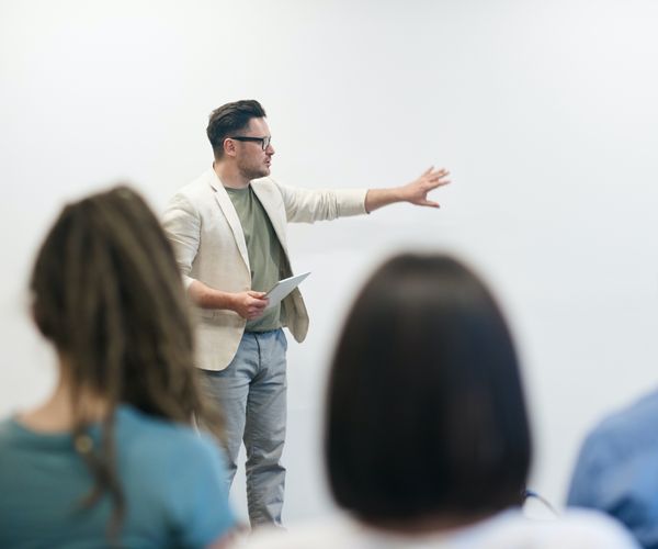 Male professor in white blazer in front of class