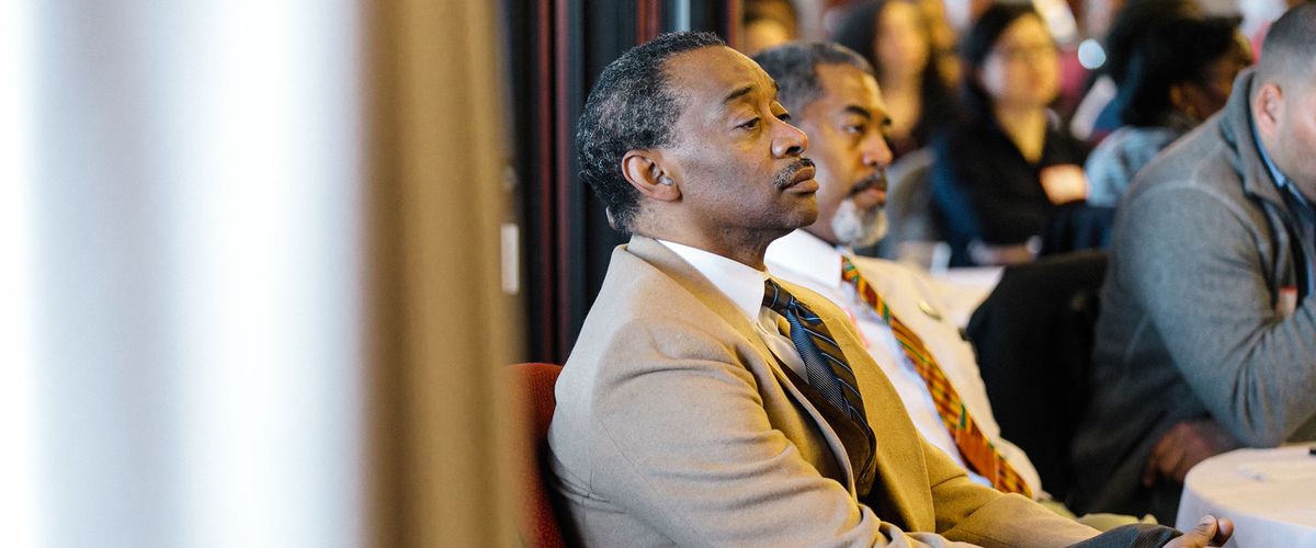 Male faculty members listening to a speaker
