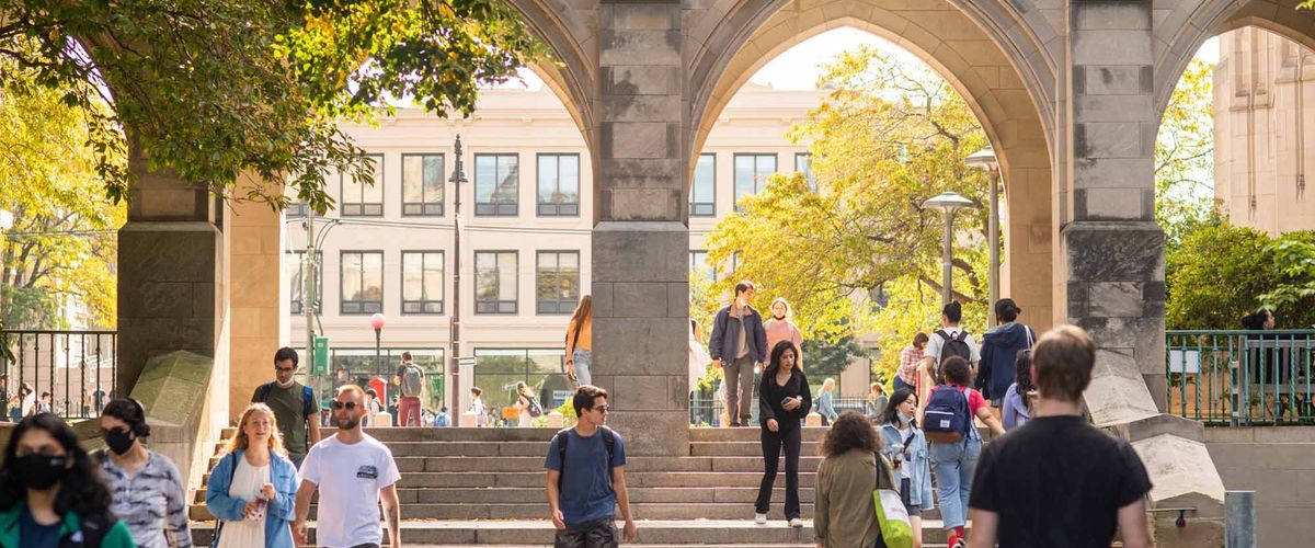 Student's walking through a stone courtyard with stone arches