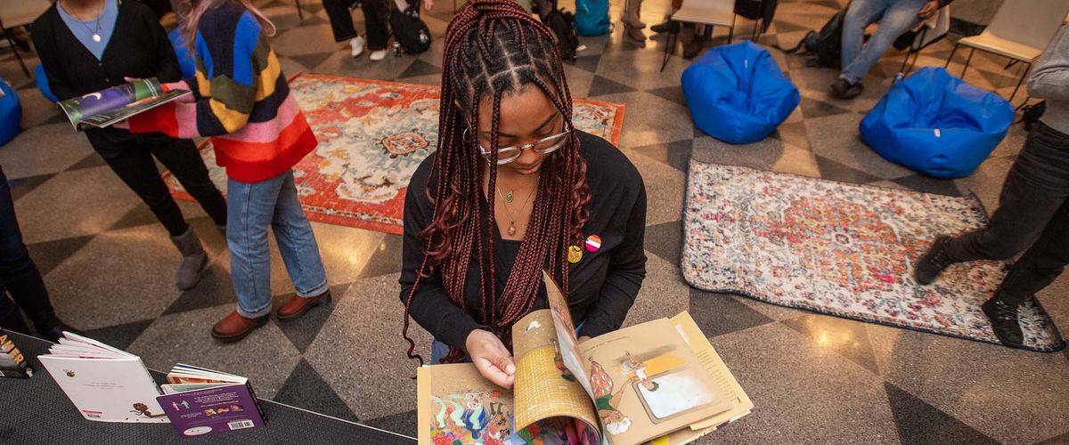 Woman reading a children's book with other people behind her