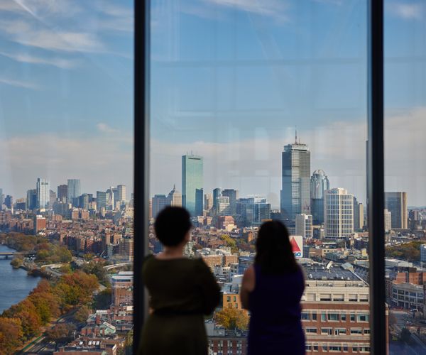 Two women in the Green Roof of the CDS building with the Boston skyline in the background.