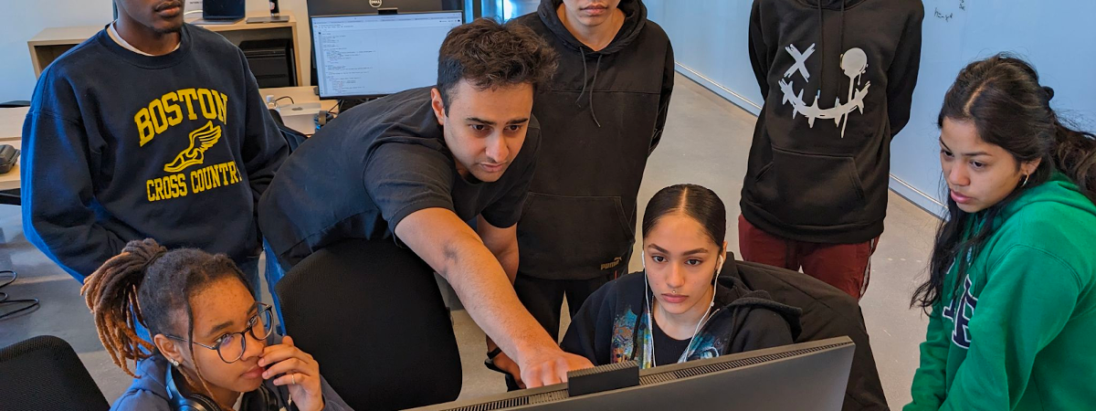 A group of software engineering students gather around a computer.