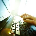 Image of a person's hands typing on a laptop keyboard