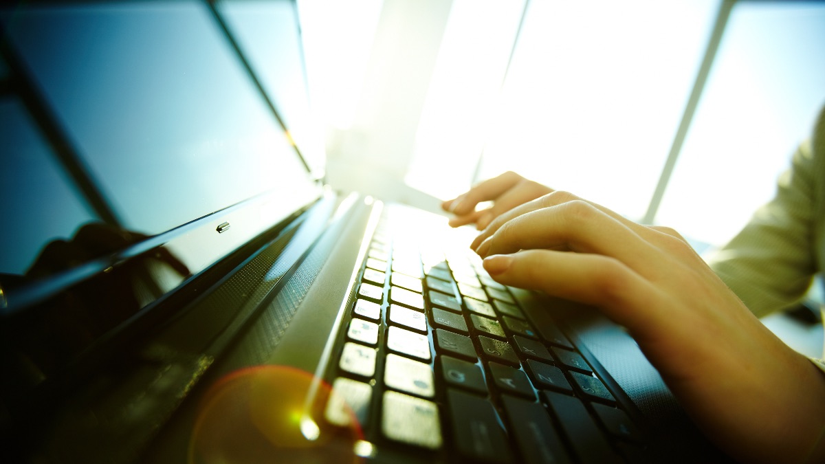 Image of a person's hands typing on a laptop keyboard
