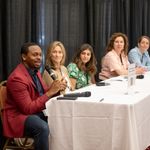 William Tomlinson is holding the microphone and speaking during the panel presentation.