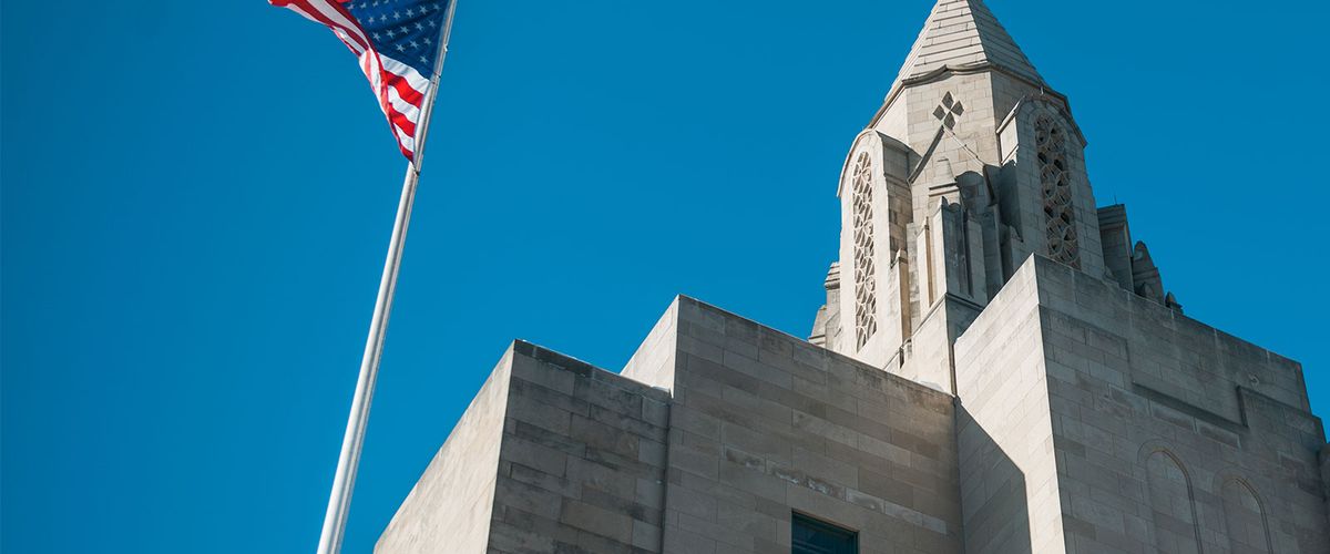 STH Tower and the American flag are seen from below on a bright, but blue and cold winter day.