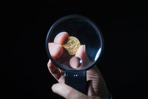 Economics professor and numismatist Pankaj Tandon holds a coin from ancient India under a magnifying glass