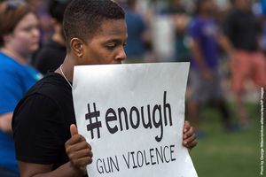 A man holds a sign «#enough gun violence» while attending a vigil in Orlando, Florida 13 June 2016.