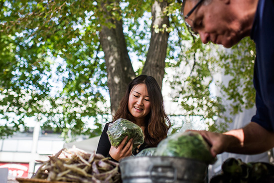 Angela Yuan (CAS’18) looks at a bag of vegetables at BU Farmers Market