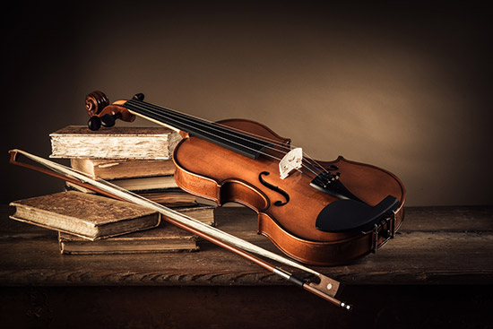 still life portrait of classic literature books and a violin symbolizing the arts