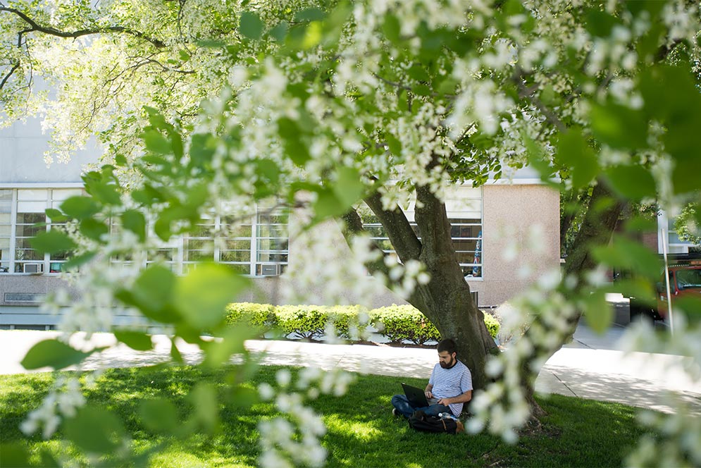 A student relaxes on the lawn outside the Boston University College of Communication building