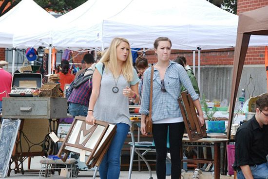 Two girlfriends shop at the Somerville flea market, vintage furniture in hand