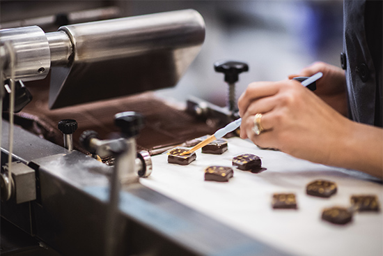 EHChocolatier founder Elaine Hsieh handpaints artisan chocolate on a conveyor belt