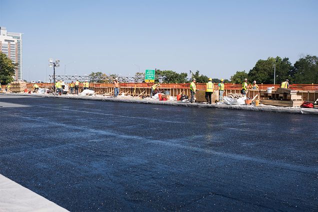 Construction workers build a parapet wall on the westbound side of the Commonwealth Ave. Bridge.