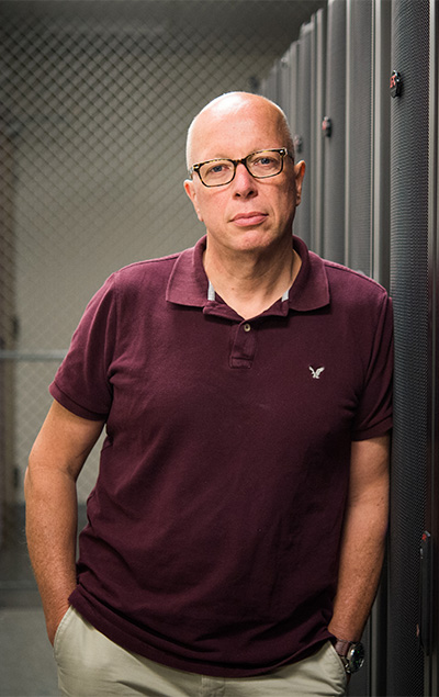 Boston University computer scientist, Mark Crovella, leaning against a row of servers.