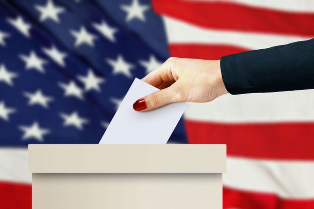 A woman drops a ballot into a ballot box