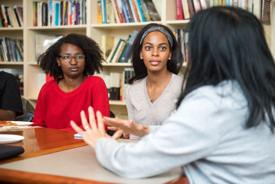 Shadae Leslie (COM'20) at left, and Nneka Oyigbo (CAS'20) listen to faculty member Sucharita Gupal