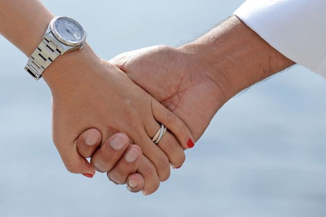 Detail photo of married couple holding hands