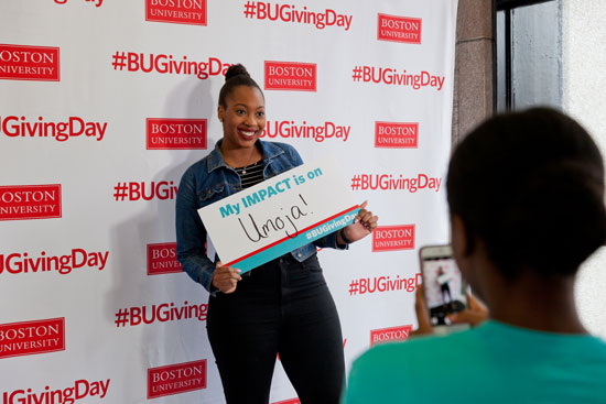 student holding a sign that says My IMPACT is on Umoja!