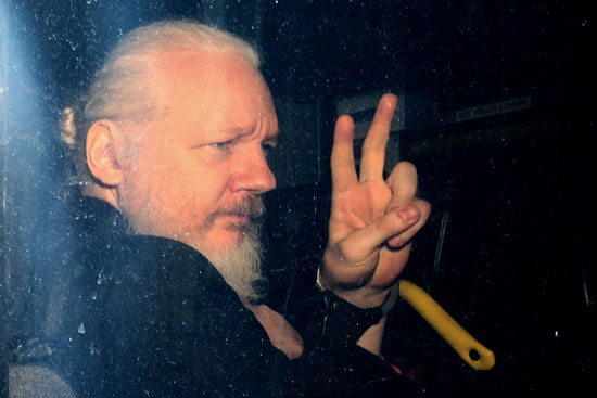 Julian Assange outside London’s Westminster Magistrates Court making a peace sign
