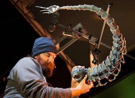 a worker posing the moon beast puppet on set