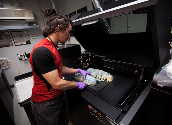 a worker wearing gloves examining a printed prototype of the moon beast