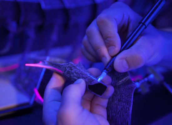 close up shot of someone painting ultraviolet paint onto pieces of the moon beast puppet