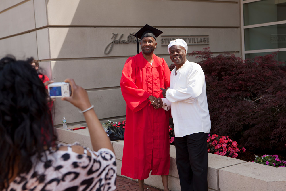 Alvino Williams, Jr. (MET '12) poses with his father Alvino Williams, Sr. while his wife and his mother Finell take photos