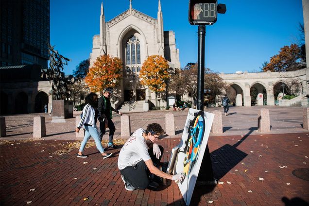 Boston University student Sam Weinerberger of Big Sam's Paints paints a mural on the sidewalk in front of Marsh Plaza.