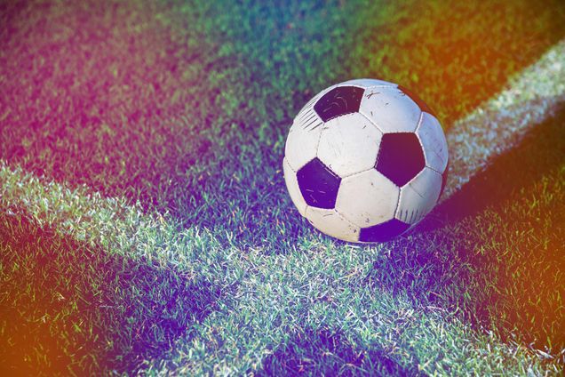 Soccer ball resting on a soccer field line with rainbow color overlay.