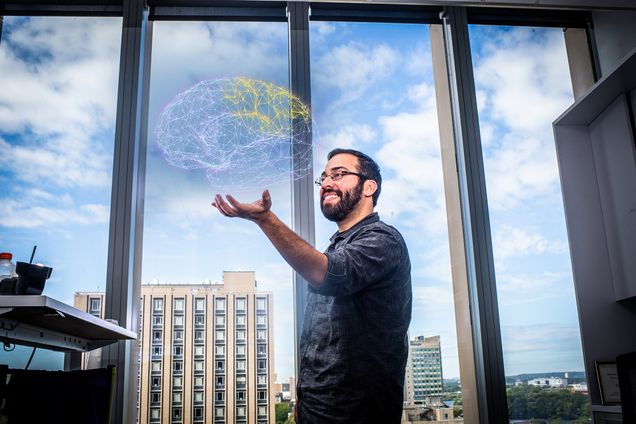 Neuroscience researcher Steve Ramirez holds a digital diagram of a brain.