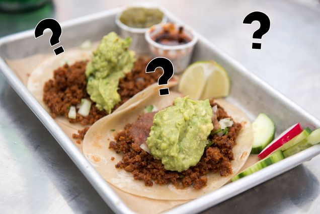 A picture of vegan chorizo tacos with question marks hanging above it