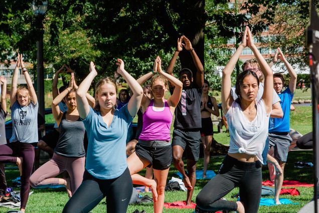 Students practice yoga outside on the “BU Beach”